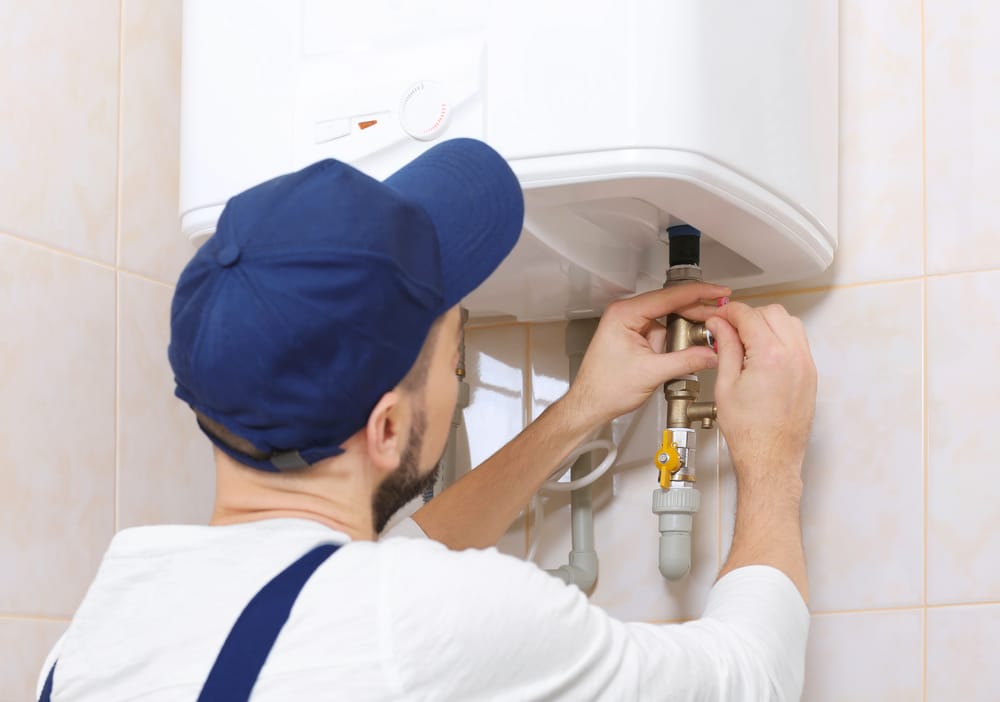 Water heater troubleshooting guide with a plumber inspecting a water heater.